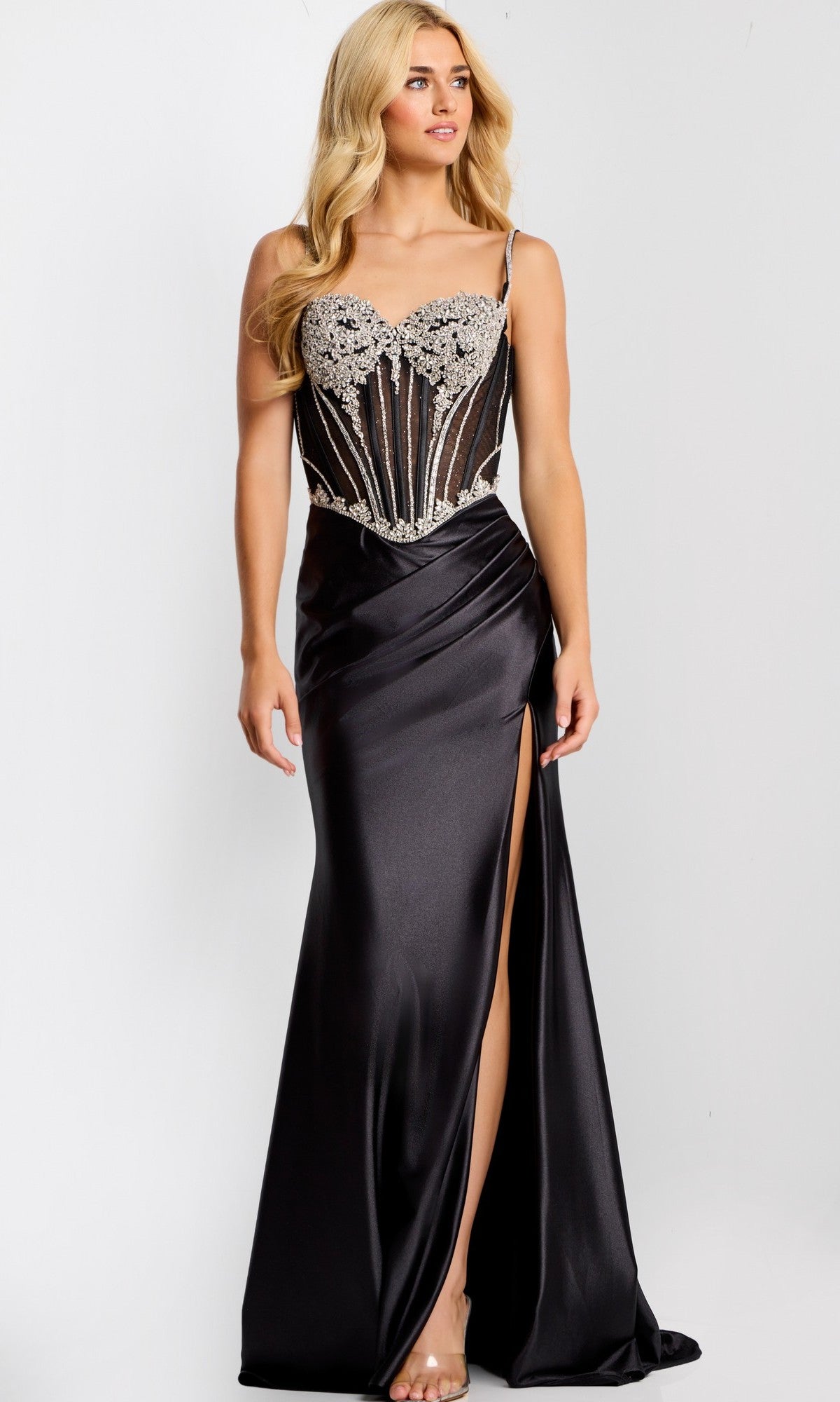A woman models the Long Prom Dress: Jovani 47849, with a satin finish, beaded corset bodice, and high slit, standing against a plain white background.